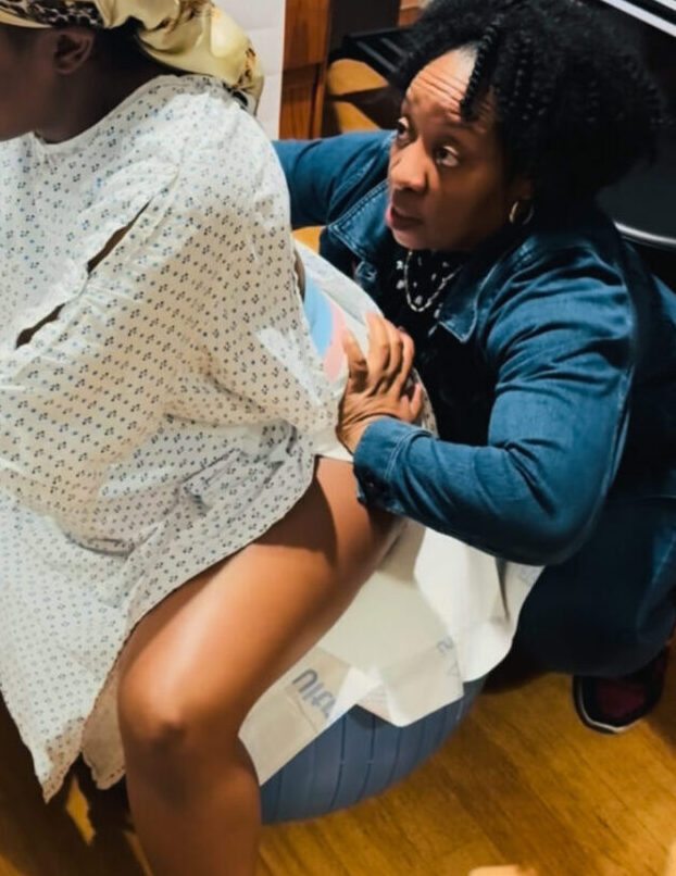 Doula Colleen performing a hip squeeze for pain relief during contractions to support a laboring mother in East Orange, NJ.